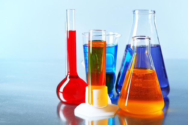 Different laboratory glassware with colorful liquid on color background
