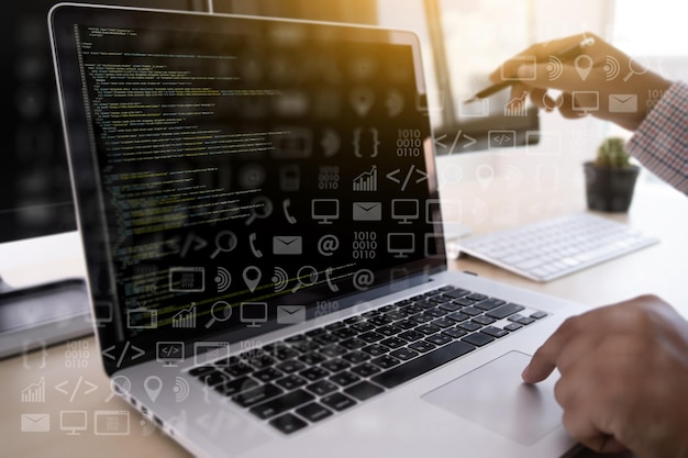 Digital composite image of businessman using laptop with icons in office