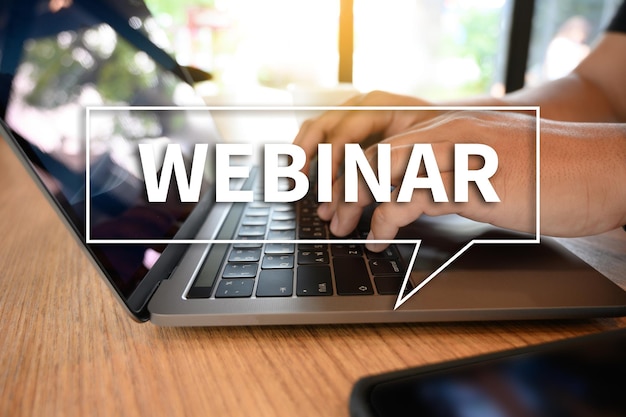 Digital composite image of webinar text against cropped hand using laptop at desk