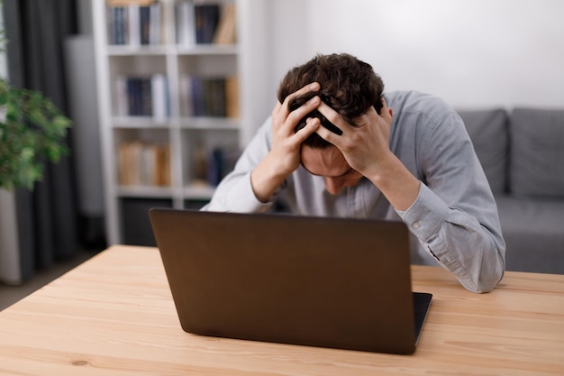 Disappointed man with laptop at home