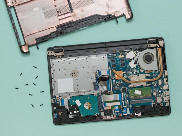 Disassembled laptop and a set of screws on a blue background