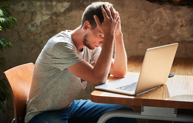 Dissapointed male with hands on face in cafe