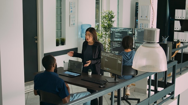 Diverse coders talking about source code on terminal window, using html script to create new interface. Team of it engineers running algorithms and checking database, doing teamwork.