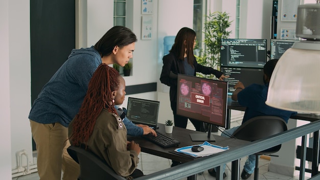 Diverse team of app developers having computer hacked and writing code, encountering unexpected system error in software development office. Coders having server failure while creating algorithm.