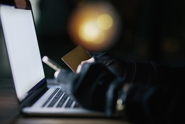 Dont let your credit card out of your sight Shot of an unidentifiable criminal using a laptop to hack into a credit account