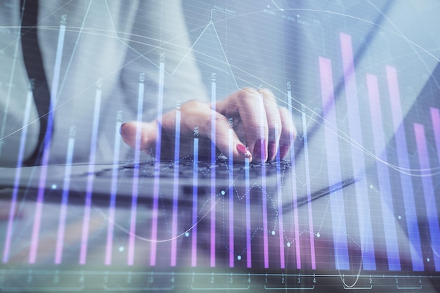 Double exposure of businesswoman hands typing on computer and financial graph hologram drawing Stock market analysis concept