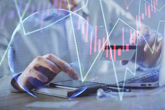 Double exposure of man hands holding a credit card and Forex graph drawing Stock trading and digital fintech in Internet Ecommerce concept