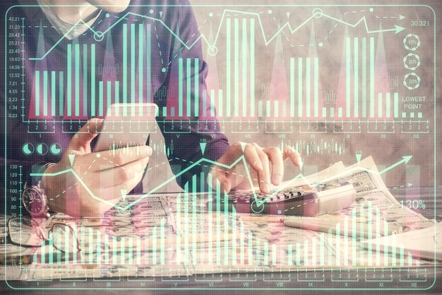 Double exposure of man's hands holding and using a digital device and forex graph drawing Financial market concept