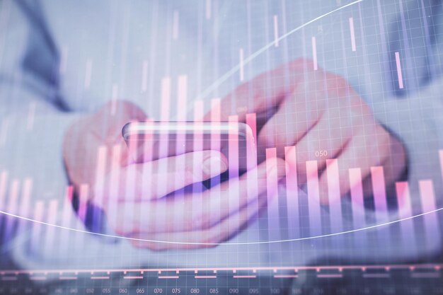 double exposure of man's hands holding and using a digital device and forex graph drawing financial market concept
