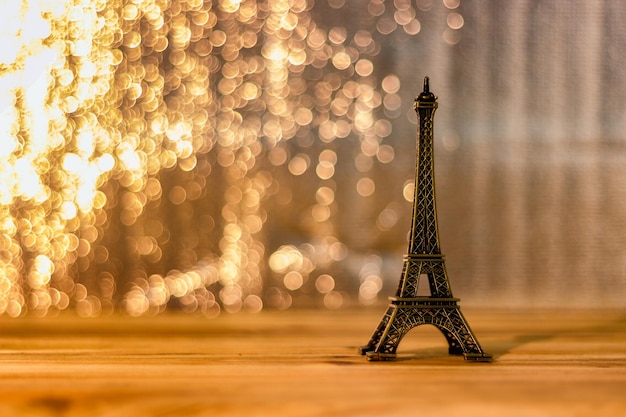 Eiffel tower souvenir on wooden table against illuminated lights