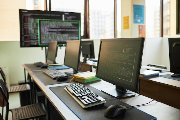 Empty computer lab featuring multiple monitors displaying programming code