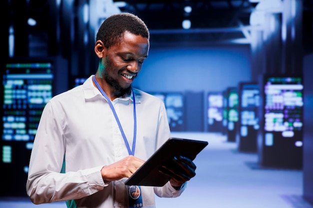 Engineer in high tech location delivering extensive computing power, capable of processing and storing vast amounts of data. Specialist walking between server rows controlling network resources