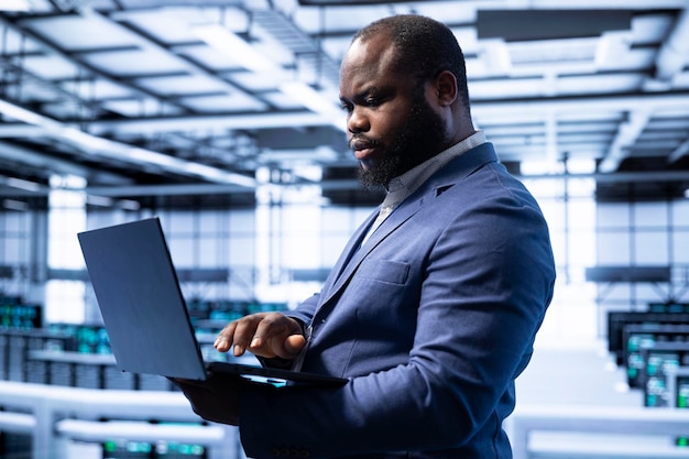 Engineer in server room installing newly ordered storage units using laptop