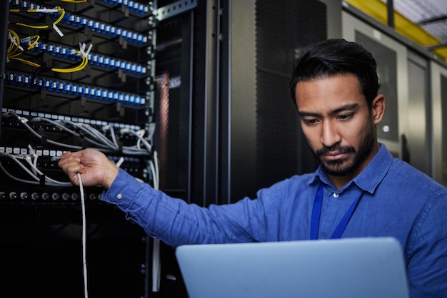 Engineer laptop server room and cable connection for software update or maintenance at night Cybersecurity coder cloud computing and programmer man with computer for networking in data center