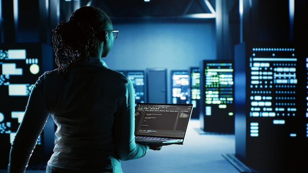 Engineer walking in server room housing advanced infrastructure storing massive datasets. Worker running code on tablet to upgrade data center rigs doing complex computational operations
