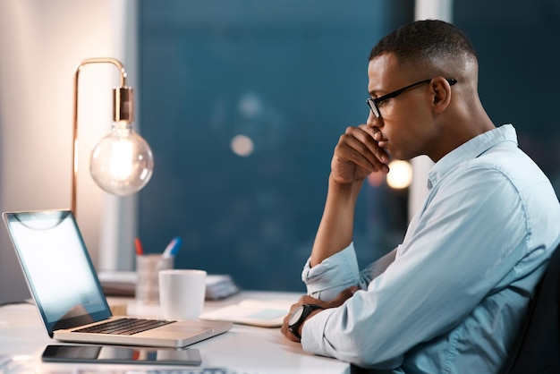 Everything starts with an idea at first Shot of a handsome young businessman working on his laptop during a late night shift at work