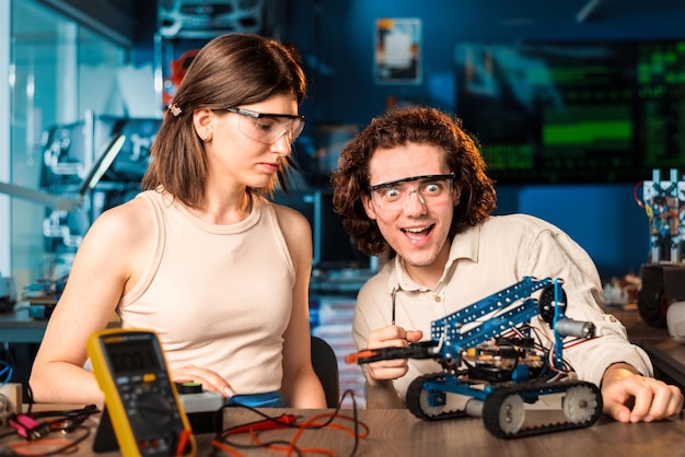 Excited young man and woman in protective glasses doing experiments in robotics in a laboratory