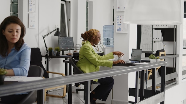 Female entrepreneur checking annual report on screen, planning business investment for company development. Startup employee checking data analytics on laptop, taking notes on files.