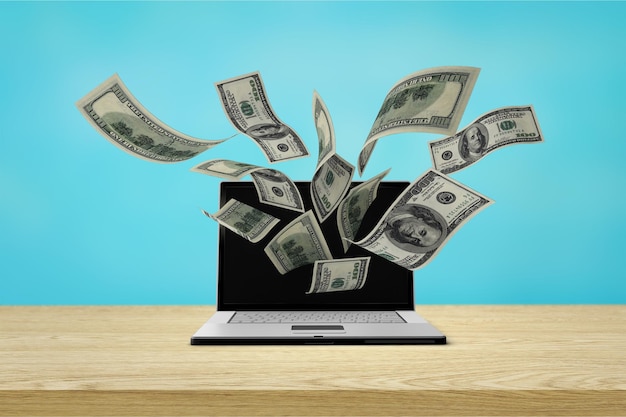finance and earning concept, one hundred dollar banknotes flying around laptop, internet,