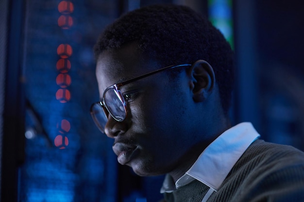 Focused young man examining server with blue lighting