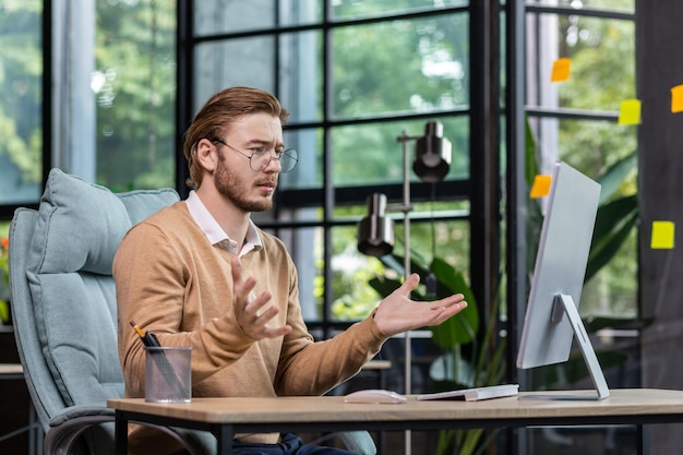 Frustrated and upset businessman reading news online from computer monitor young blond man sad at
