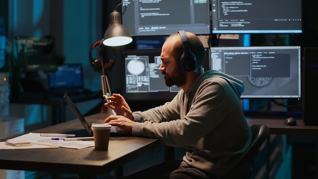 Funny programmer listening to music and playing air drums, fooling around in office. Young male coder having fun with instrument, acting silly and careless singing song on headset.
