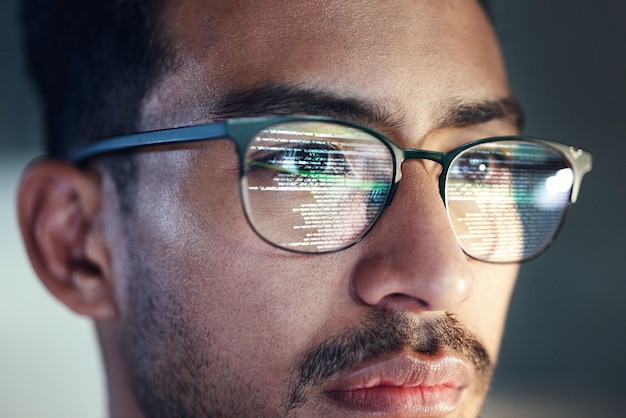 Glasses man and reflection of programmer on computer working on software code and data IT engineer and serious face of developer with information technology for cloud computing in office closeup