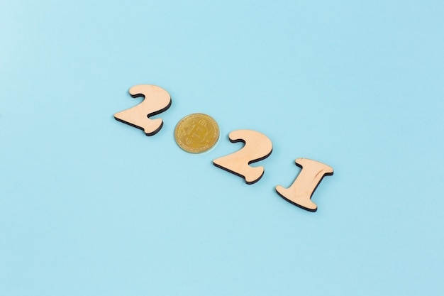 Gold bitcoin and wooden numbers 2021 lies on a blue surface