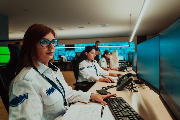 Group of female security operators working in a data system control room Technical Operators Working at workstation with multiple displays security guards working on multiple monitors in surveillan
