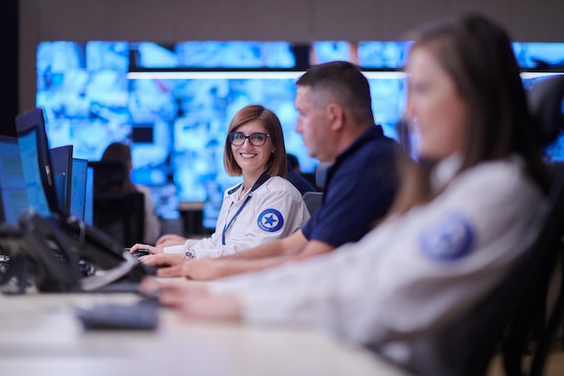 Group of Security data center operators working in a CCTV monitoring room looking on multiple monitors  Officers Monitoring Multiple Screens for Suspicious Activities  Team working on the System Contr