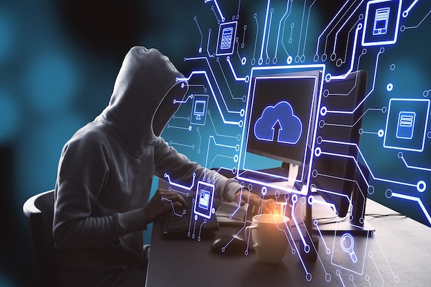 Hacker at desktop using computers with abstract glowing circuit cloud computing interface on blurry blue bokeh background Information technology hacking and network concept
