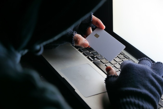 Hacker hand stealing data from credit card .
