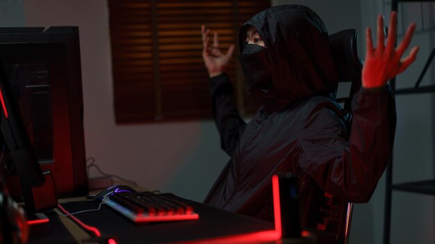 Hacker in hoodie raising hands while having problem with hacking programming system or server
