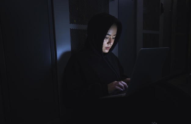 Hacker server room and person on laptop for coding software data center crime and cyberpunk in dark Network hacking woman or user in cybersecurity information technology or programmer ransomware