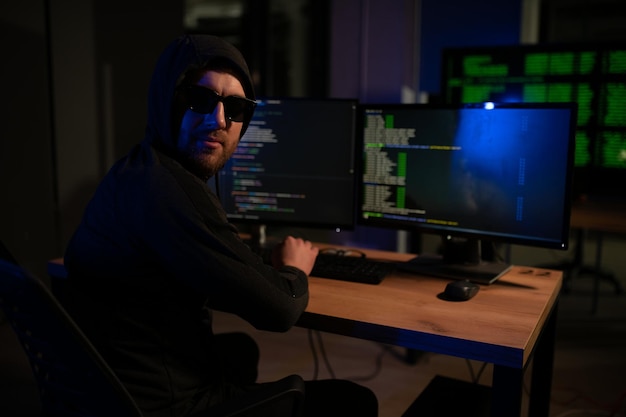 hacker sitting at desk in dark atmosphere A computer programmer or hacker Anonymous computer hacker