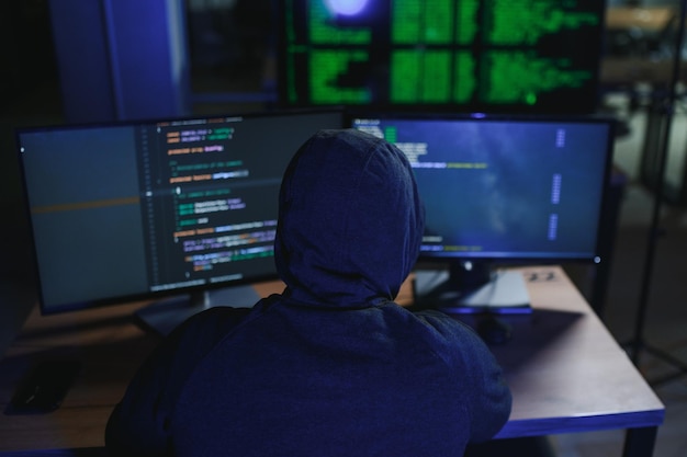 hacker sitting at desk in dark atmosphere A computer programmer or hacker Anonymous computer hacker