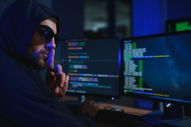 hacker sitting at desk in dark atmosphere A computer programmer or hacker Anonymous computer hacker