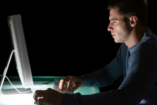 Handsome serious computer engineer looking at computer at night