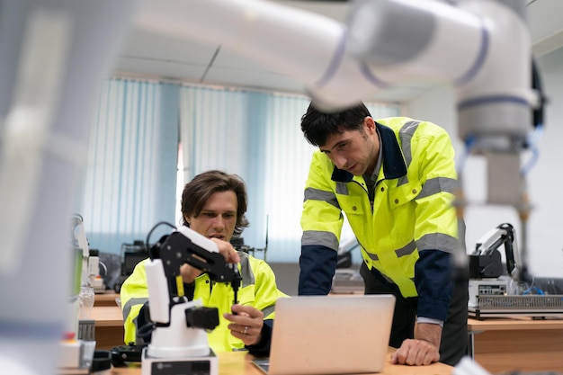 Insinööri tarkastaa ja ohjaa automaatiorobottivarsikoneita älykkäässä teollisuustehtaassa reaaliaikaisen valvontajärjestelmän ohjelmistorobotiikan ja digitaalisen valmistuksen toiminnan avulla