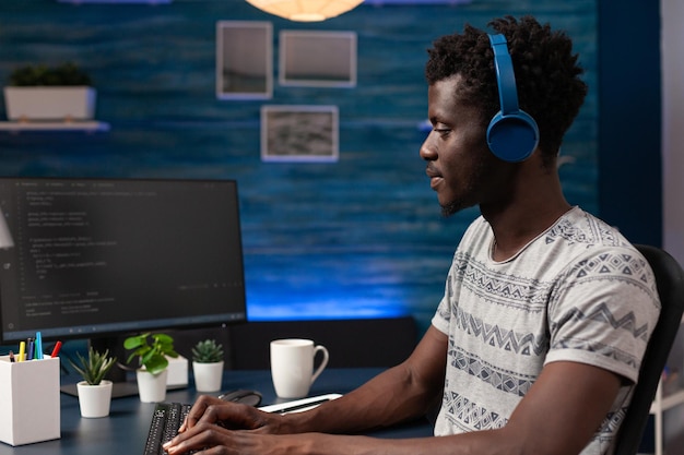 It businessman wearing headphones programming codes for firewall server on computer working remote from home. Hacker man typing infographics javascript writing artificial intelligence algorithm