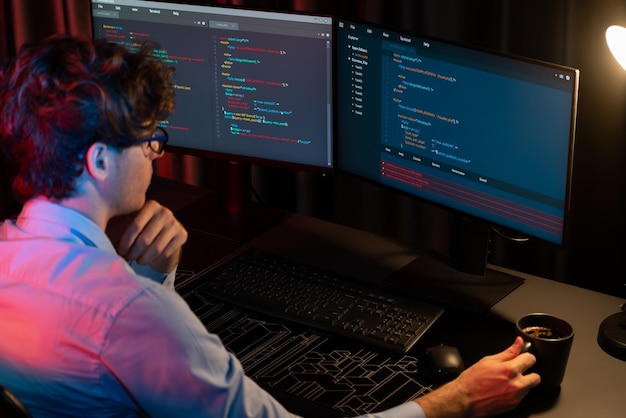it developer concentrating software while drinking coffee at neon light gusher