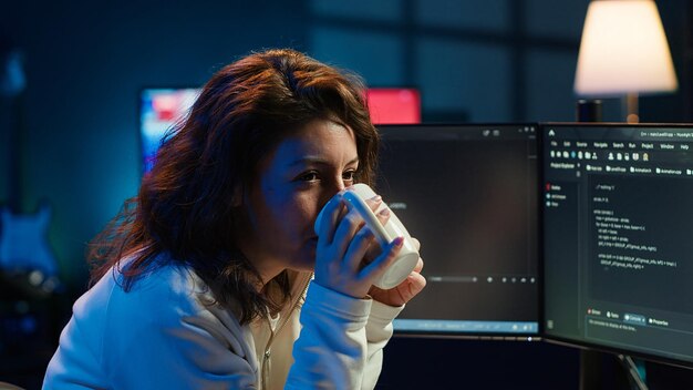 Joyful IT worker holding coffee mug and debugging code
