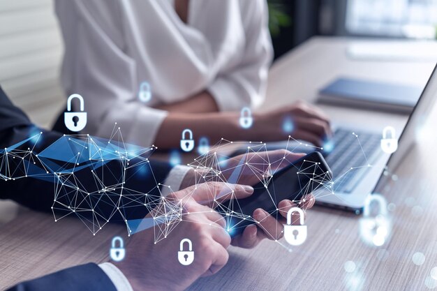 Kaksi liikemiestä virallisissa vaatteissa työskentelevät projektissa suojellakseen kansainvälisen yrityksen kyberturvallisuutta älypuhelimen ja kannettavan tietokoneen avulla. Riippulukko hologrammikuvakkeet Tiimityöskentelykonsepti