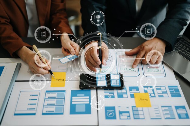 Lähikuva käyttöliittymäkehittäjätiimin aivoriihistä projektissaan kannettavan älypuhelimen ja digitaalisen tabletin kanssa. Luova digitaalinen kehitystoimisto, jossa on virtuaalikuvakkeita