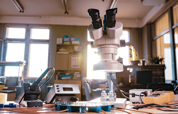 large modern electron microscope. microwave coaxial connector and electronic digital multimeter on workshop table. research of high-frequency radio electronic components in a scientific laboratory