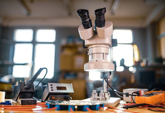 large modern electron microscope. microwave coaxial connector and electronic digital multimeter on workshop table. research of high-frequency radio electronic components in a scientific laboratory
