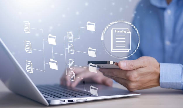 Liikemies työskentelee kannettavalla tietokoneella ja käyttää virtuaalinäyttöä. Online-dokumentaatio tietokanta IT-konsultti on asettamassa Virtual Document Management System -järjestelmää kannettavalla tietokoneella. Ohjelmisto yritystiedostojen arkistointiin