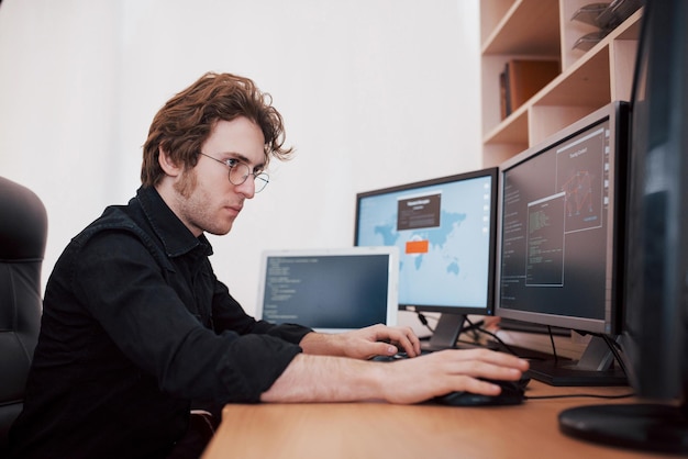 Male programmer working on desktop computer with many monitors at office in software develop company Website design programming and coding technologies