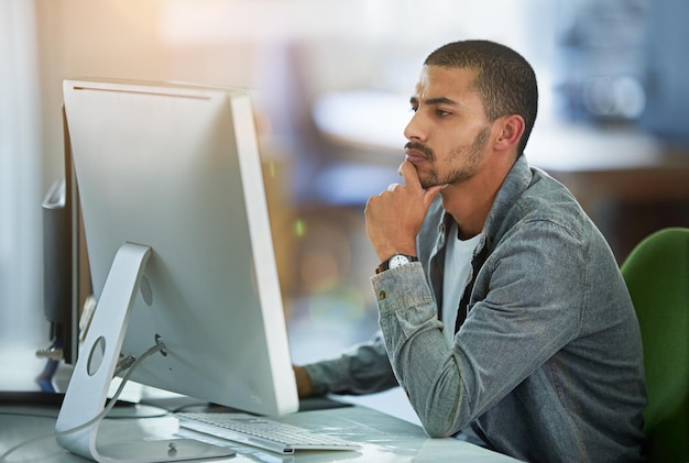 Man computer and thinking for graphic design in office for software programming thoughts or project planning Male person desktop and it decision with media research for networking skill or ideas