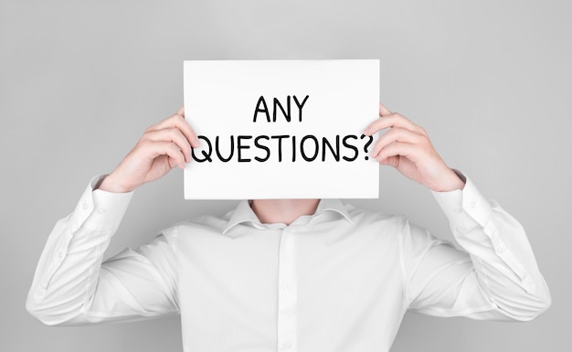 man covers his face with white paper with text any questions